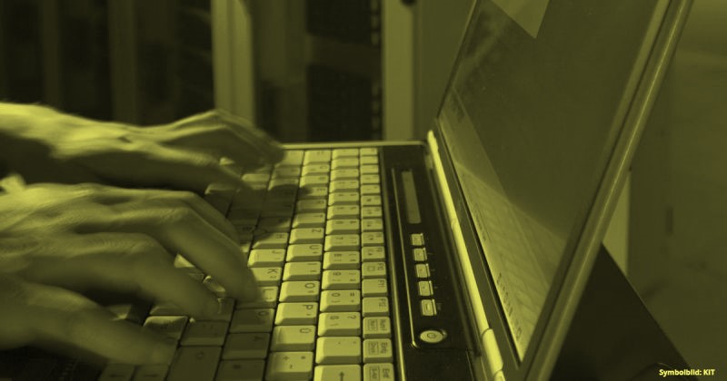 Person, die vor einem Computer sitzt und in die Tastatur tippt